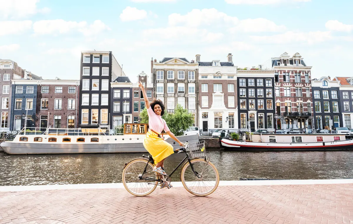 Blije vrouw fietsend langs water in Amsterdam