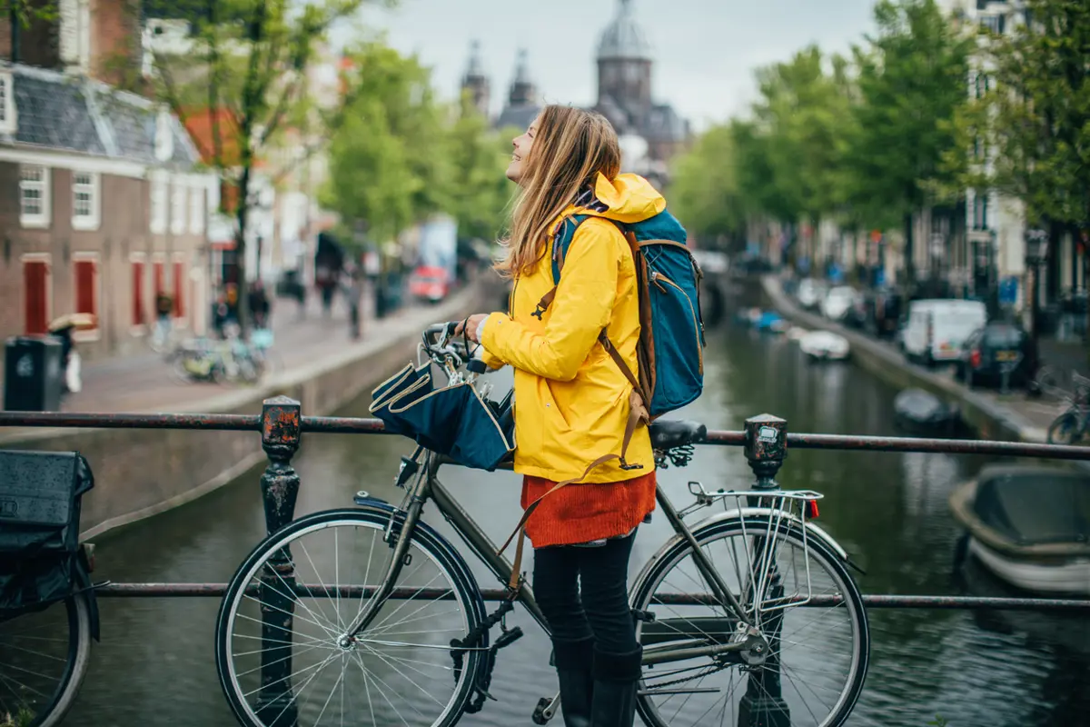 Vrouw staat met fiets op brug in Amsterdam