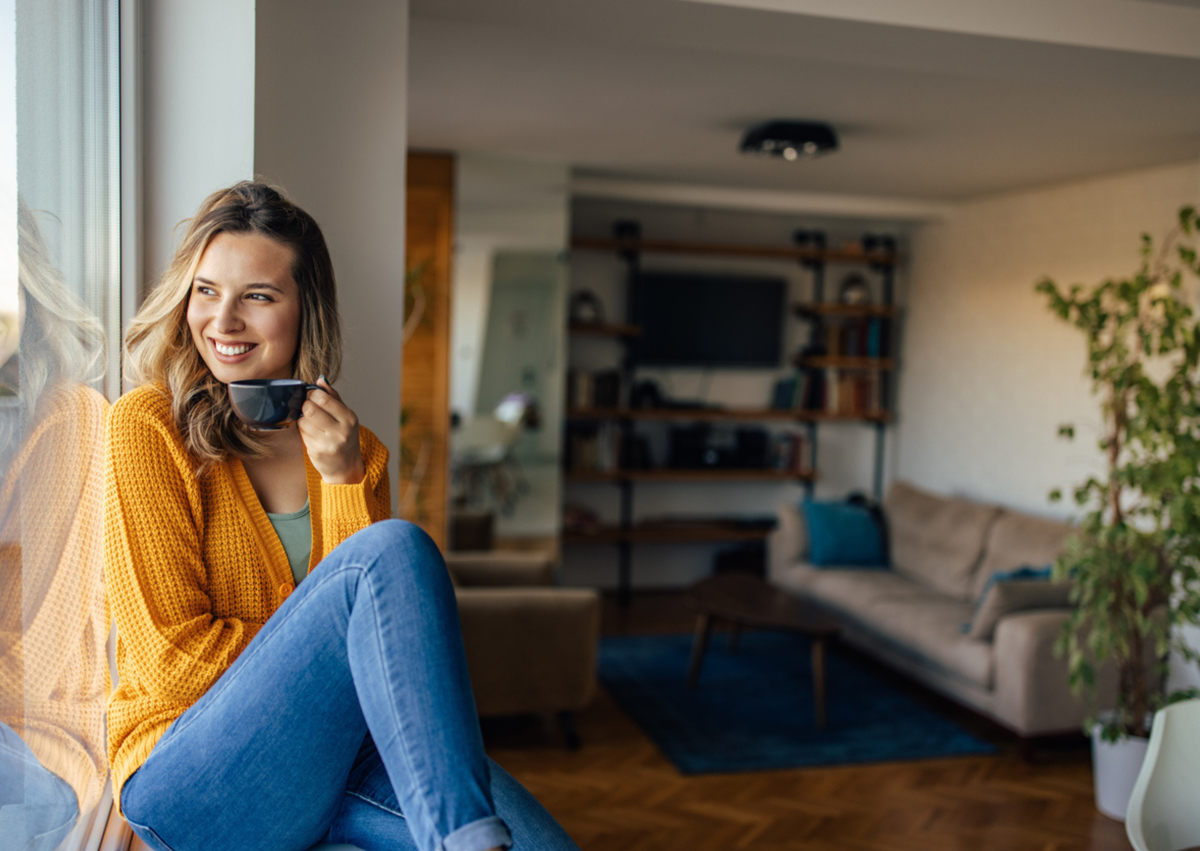 vrouw drinkt thuis koffie tegen raam